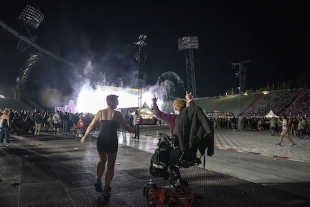 Zwei weibliche Fans feiern vor der Bühne. Der Rollsttuhl fällt nicht ins Gewicht, sondern ist nur Mittel zum Zweck