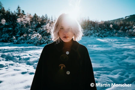 Die Singer und Songwriterin Avec im Schnee. Von hinten blendet die Sonne und so ist das Gesicht nicht komplett zu erkennen