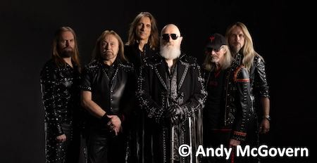 Die Band Judas Priest, ganz in Schwarz gekleidet. Im Vordergrund steht Rob mit seinem langen weißen Bart.