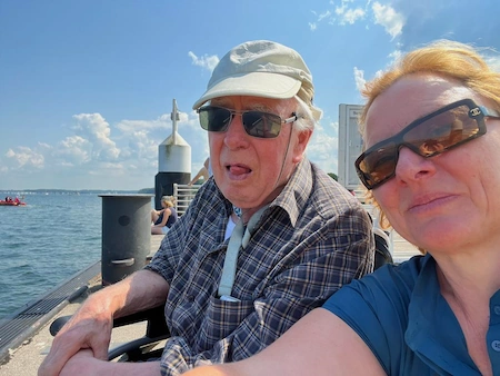 Milli und Herr G stehen mit Sonnenbrillen am Kay. Sie schauen auf die Bucht und genießen das schöne Wetter auf der Kieler Woche.