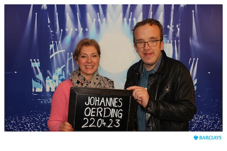 Susanne und Octavius halten gemeinsam ein Schild mit dem Konzerttermin von Johannes Oerding. Sie lächeln glücklich in die Kamera