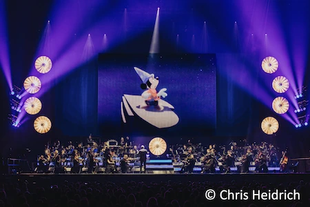 Bei DISNEY IN CONCERT dreht sich alles rund um die Maus. Hier ist Mickey als der Zauberlehrling zu sehen, davor ein großes Orchester